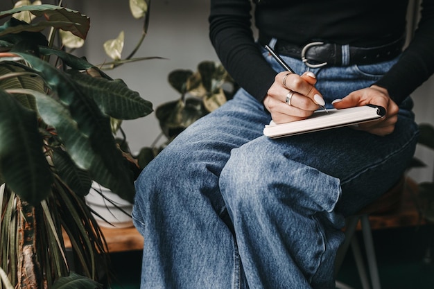 Woman is sitting on a chair and writing in her notebook.