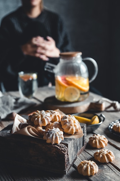 Woman is sitting over a cup of Hot tea with slices of fresh grapefruit on wooden tablet