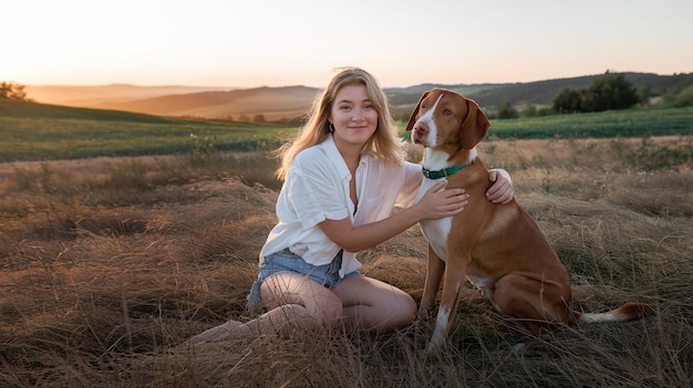 a woman is sitting in a field with a dog