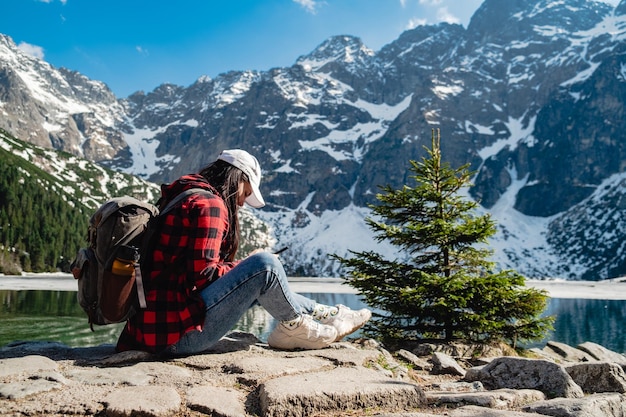 A woman is sitting on the shore of a lake Morskie Oko Tatras mountains