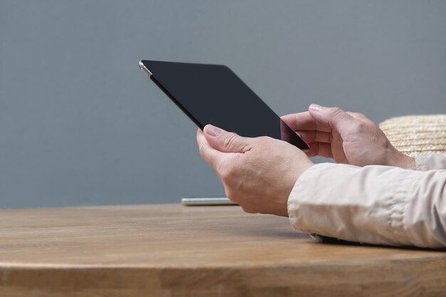 A woman is sitting at a table in a cafe with a tablet in her hands.