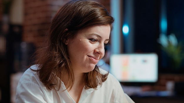 a woman is smiling at the camera with a computer in the background