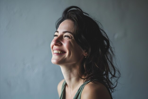 A woman is smiling while standing in front of a gray wall