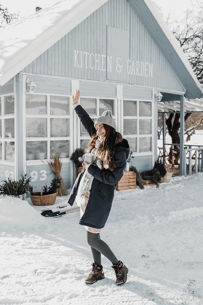 Woman is standing by the house during winter and is enjoying the sun