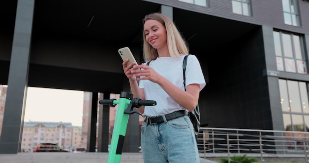 Woman is using smartphone after ride on electric kick scooter Driving ecology transportation