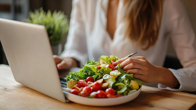 Photo a woman is working on a laptop and a salad is on a plate