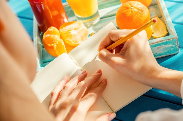 Woman is writing in her notebook in the sunny morning