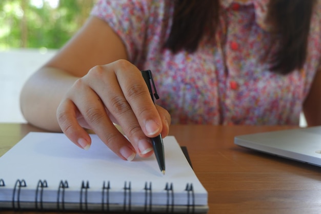 Photo a woman is writing in a notebook with a pen