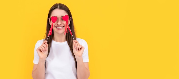 Woman isolated face portrait banner with copy space smiling girl with love symbol on yellow background love romantic gift sweetheart