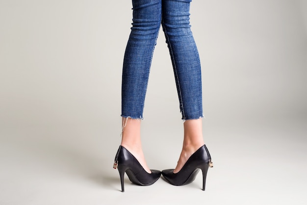 Woman in jeans black high heel shoes with a padlock posing