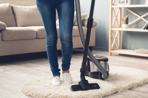 woman in jeans using a vacuum cleaner