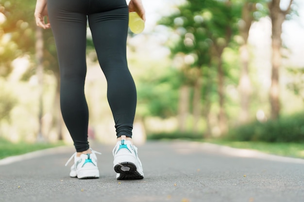 Woman jogging and walking on the road at morning Young adult female in sport shoes running in the park outside leg muscles of Athlete Exercise wellness healthy lifestyle and workout concepts