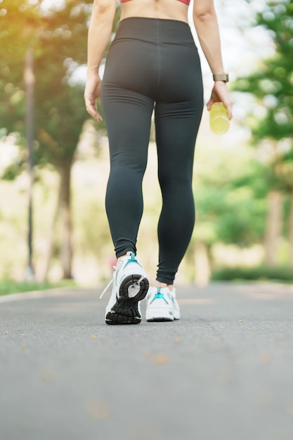 Woman jogging and walking on the road at morning Young adult female in sport shoes running in the park outside leg muscles of Athlete Exercise wellness healthy lifestyle and workout concepts