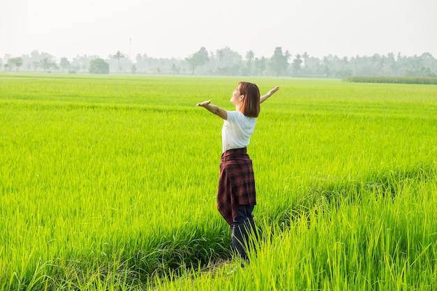 A woman joyfully jumps in a sunny field surrounded by the beauty of nature embodying freedom and happiness