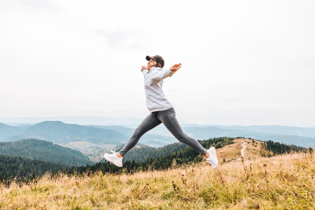 woman jumping at the peak of the mountain beautiful view of valley at background hiking concept