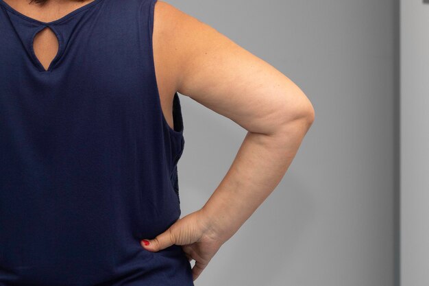 Woman keeping flabby arm on waist back view