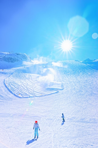 Woman and kid Skiers skiing in Hintertux Glacier in Tyrol in Mayrhofen, Austria, winter Alps. Lady and chuld Ski at Hintertuxer Gletscher in Alpine mountains with white snow and blue sky. Sun shining