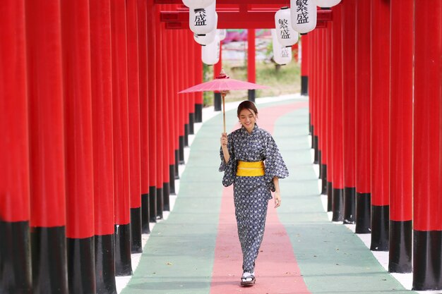 a woman in kimono holding umbrella walking into at the shrine, in Japanese garden.