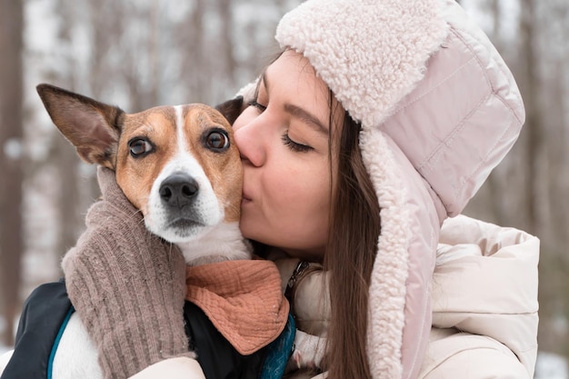 woman kissing dog walking in winter park