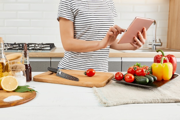 Woman In Kitchen Following Recipe On Digital Tablet. Kitchen background