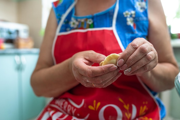 a woman in the kitchen prepares dumplings from dough and minced meat