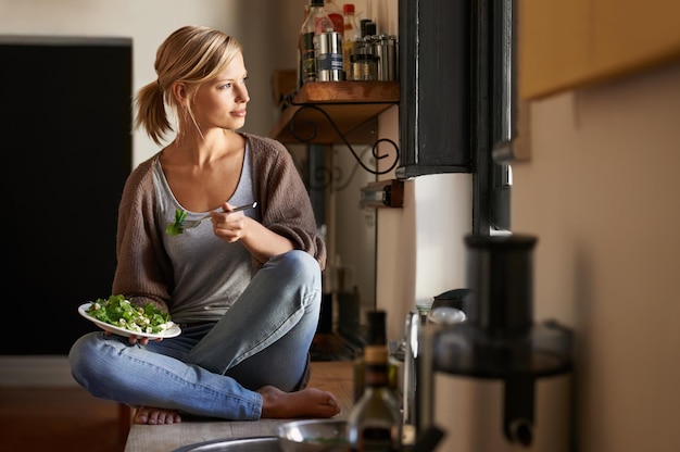 Woman kitchen and salad with smile break and home for nutrition vegetables and diet Designer house and lunch for health wellness and relaxation and break for wellbeing rest and happiness