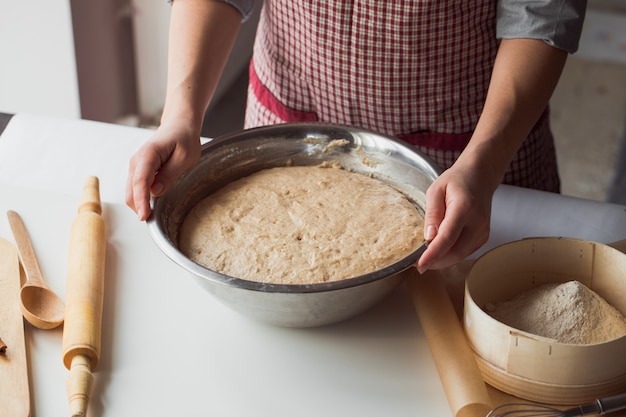 Woman kneading dough on kitchen table