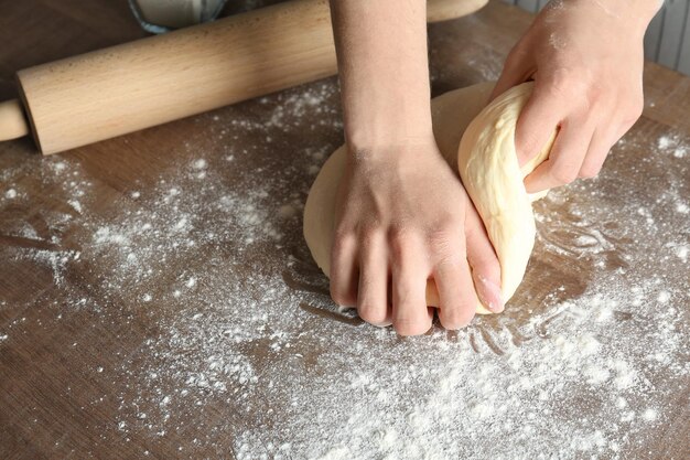 Woman kneading dough on kitchen table