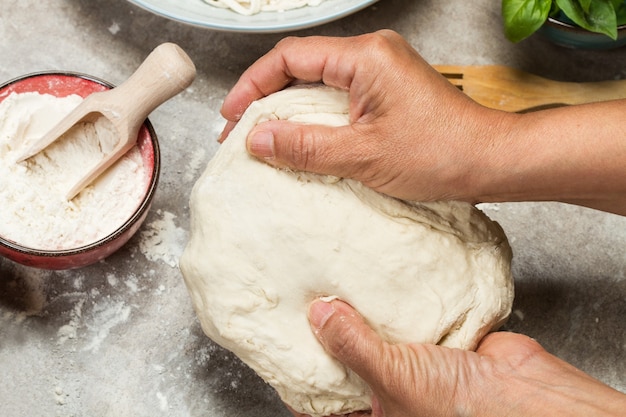 Woman kneading a dough with her hands on a wooden table