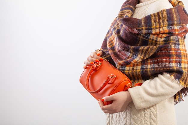 woman in knitted sweater with orange handbag on white background