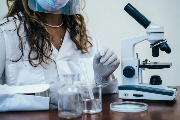 Photo a woman in a lab coat is using a microscope