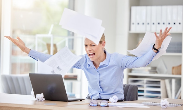 Woman laptop and stress with flying paper anxiety and burnout with 404 technology glitch in a business office Angry frustrated worker and shouting employee with target audience research documents