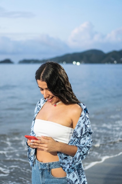 Woman Laughing While Using Mobile Phone At The Beach