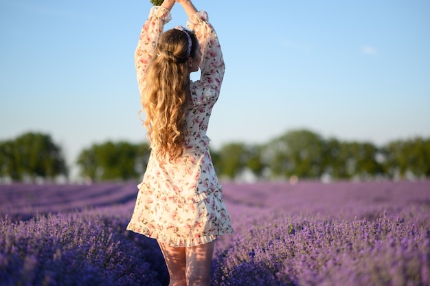 Woman in lavender field at sunset wearing summer dress