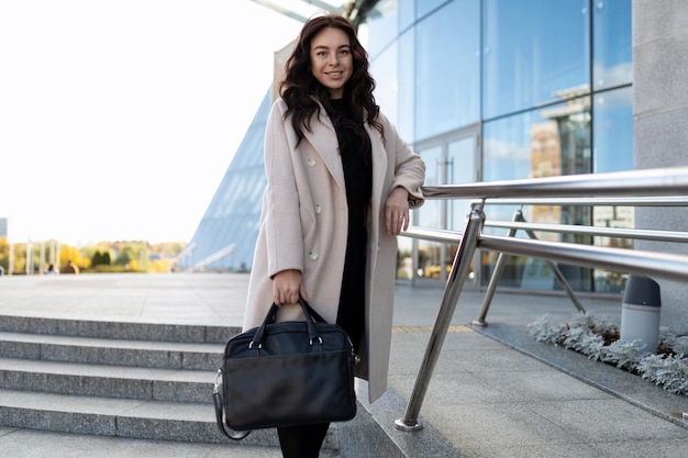 A woman lawyer with a briefcase for documents stands next to an office building