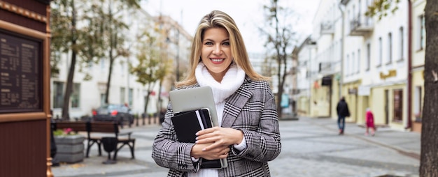 A woman lawyer with a laptop in her hands on the background of the city panorama with a smile looks