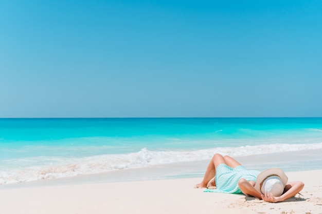 Woman laying on the beach enjoying summer holidays looking at the sea