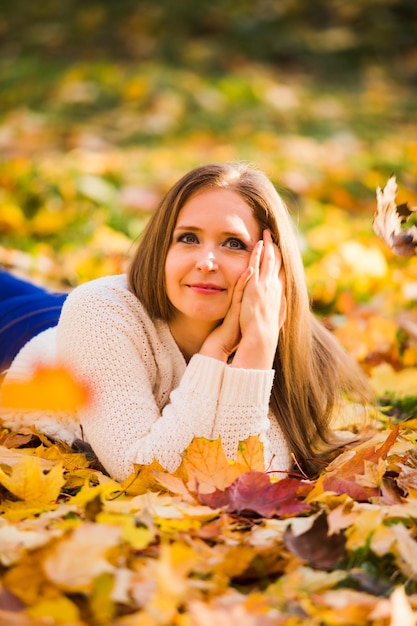 Woman laying in maple leaves in the park