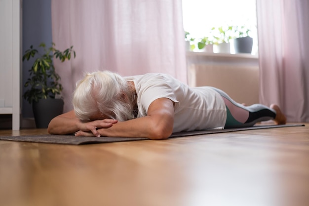 Woman laying on yoga mat and relaxing while enjoying yoga at home