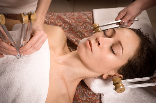 woman lays on massage table at sound therapy and healing acutonics session with tuning forks