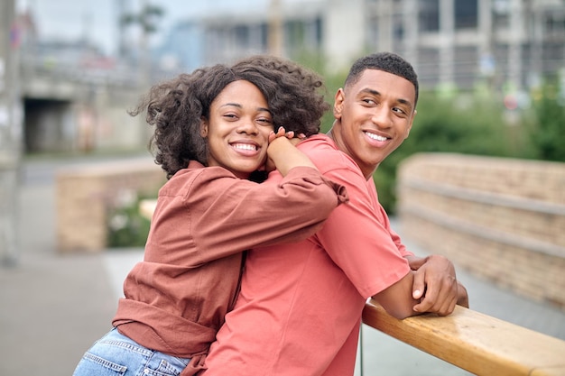 Woman leaning on back of man standing sideways to camera