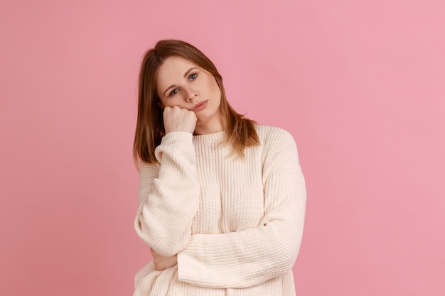 Woman leaning on hand and expressing disinterest apathy with dull look feeling lazy indifferent