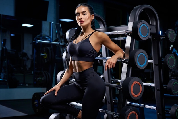 Woman leaning on stand with barbells