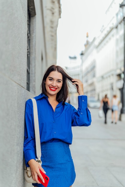 Woman leaning on the wall smiling looking at the camera in the city