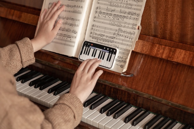 Woman learns to play the piano using the phone, music lesson, online training.