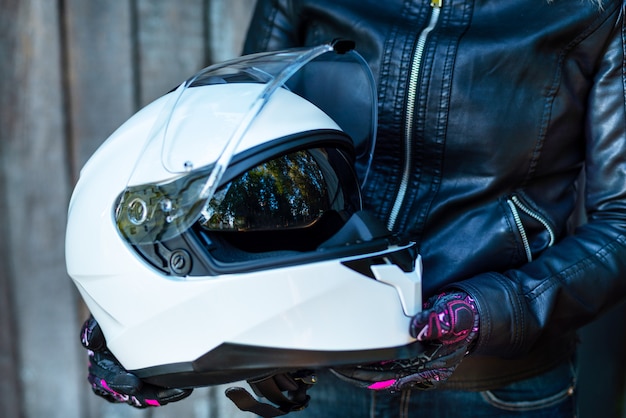 Woman in leather jacket holds motorcycle helmet