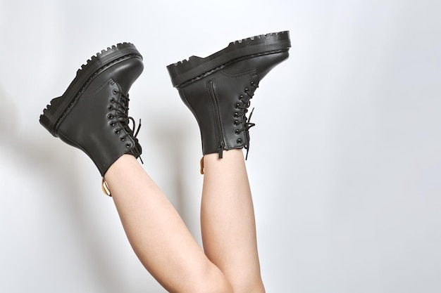 Woman legs in black combat boots on high heel platform with lug soles upside down white background