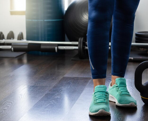 Woman legs in the gym next to dumbbell