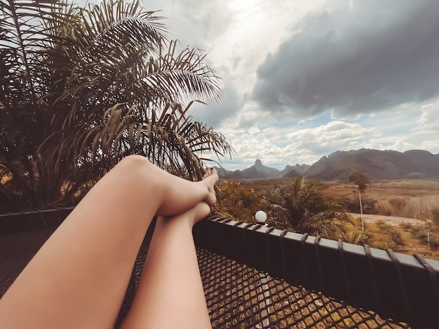 Woman legs in a hammock watch mountain landscape