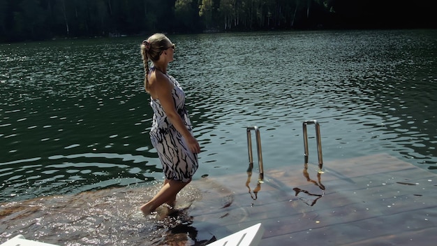 Woman lie on a sunbed in sunglasses and a boho silk shawl Girl rest on a flood wood underwater pier The pavement is covered with water in the lake